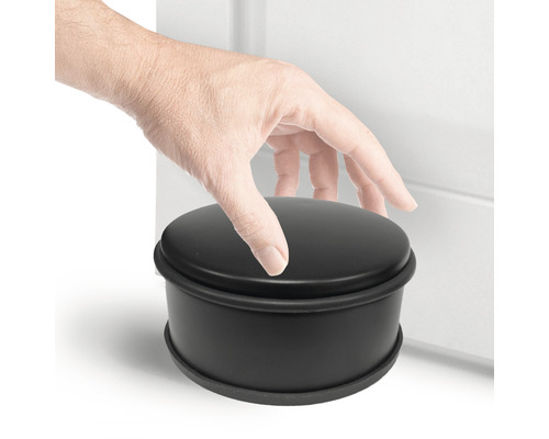 Schwarzer runder Türstopper neben einer Tür mit einer Hand darauf