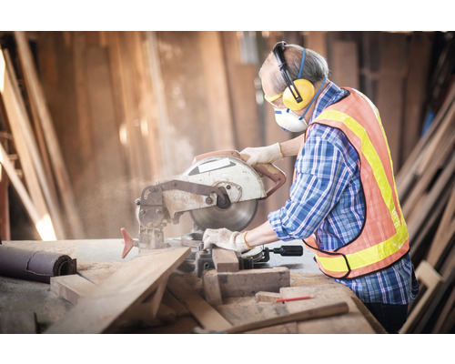 Artisan avec mesures de protection lors du travail du bois avec une scie circulaire