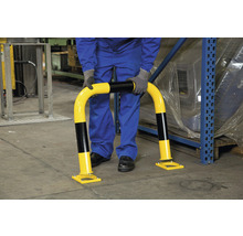 Une personne installe une barrière de protection anti-collision dans un entrepôt.