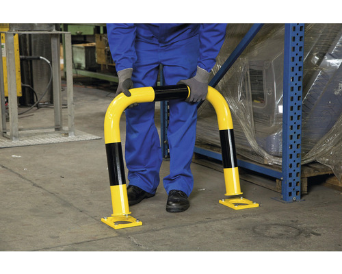 Une personne installe une barrière de protection anti-collision dans un entrepôt.