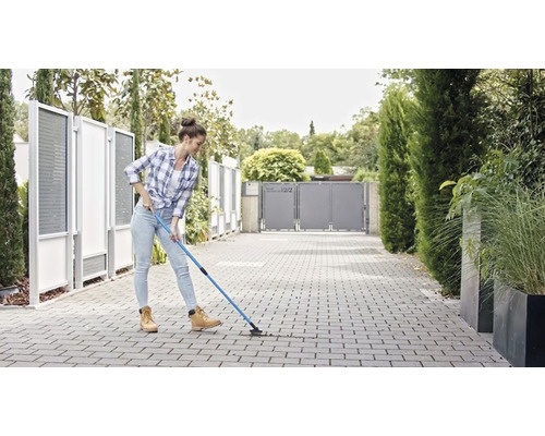 Une femme nettoie des pavés avec un nettoyeur de joints à l''extérieur.