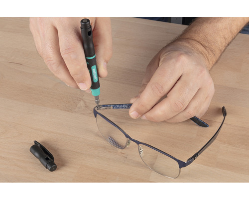 Eine Person repariert eine Brille mit einem Präzisionsschraubendreher.