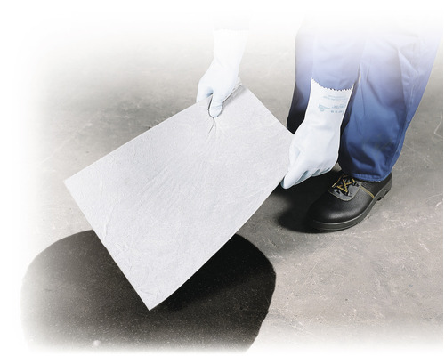 Une personne gantée tient un tampon d''absorption d''huile au-dessus d''une tache d''huile.