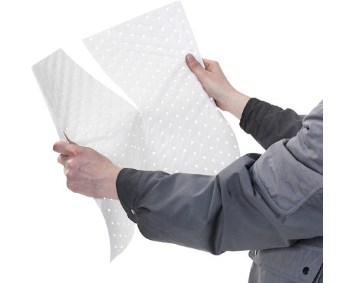 Une personne tient des feuilles absorbantes d''huile perforées dans ses mains.