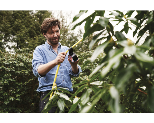 Mann repariert gelben Schlauch im Garten mit Isolierband