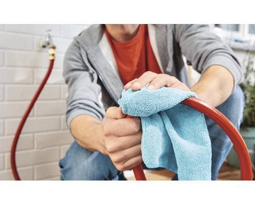 Eine Person reinigt einen Schlauch mit einem Tuch