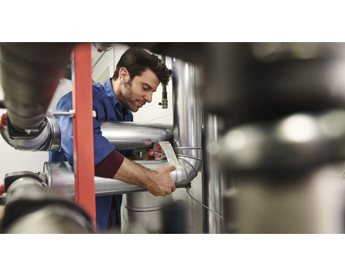 Un homme enroule un tuyau avec du ruban d''étanchéité.