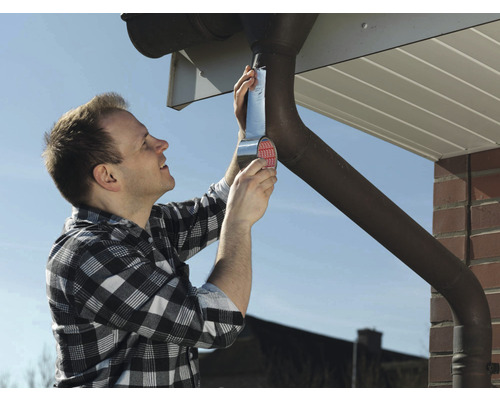 Un homme répare une gouttière avec du ruban d''étanchéité.