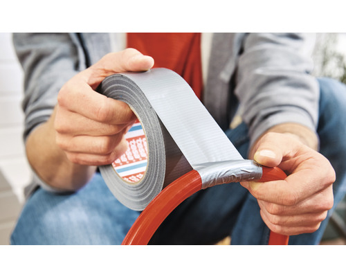 Un homme répare un tuyau avec du ruban adhésif toilé