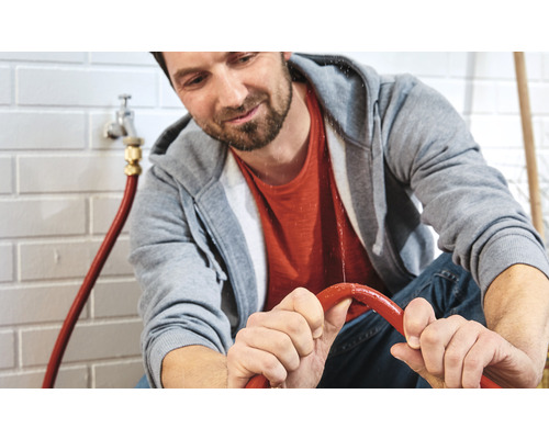 Homme réparant un tuyau d''arrosage qui fuit