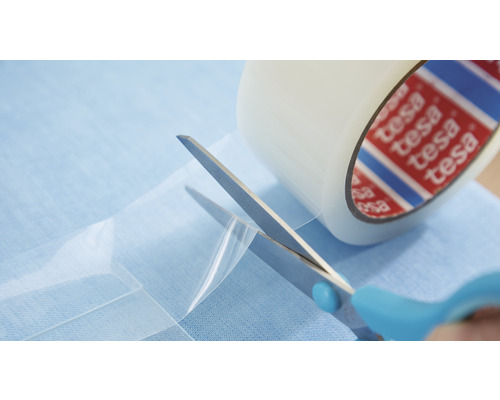 Eine Rolle Tesa-Film wird mit einer Schere geschnitten.