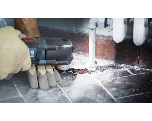 Utilisateur avec outil multifonction lors de travaux de rénovation dans la salle de bains