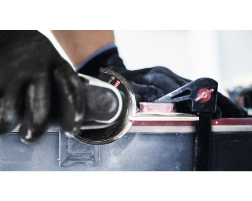 Coupe-carrelage en cours d''utilisation avec gants et serre-joint