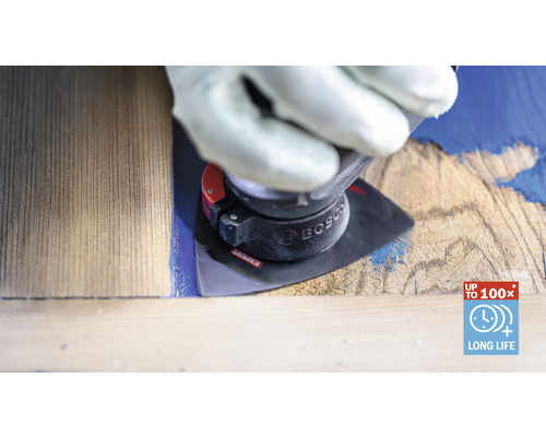 Un homme ganté utilise un outil de ponçage sur une pièce de bois pour enlever de la peinture. Logo Bosch.