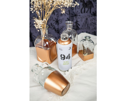 Des bouteilles décoratives en verre avec des accents de couleur et un aérosol sont posés sur un tissu.