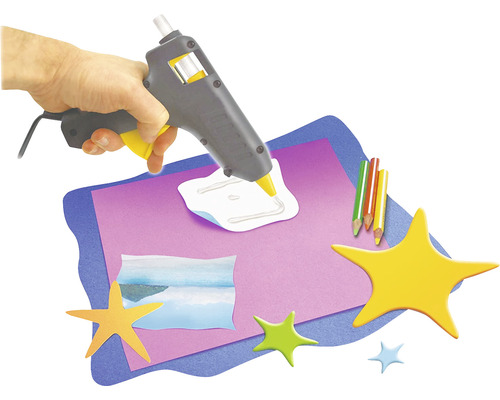 Pistolet à colle chaude en cours d''utilisation avec du papier et des étoiles pour le bricolage