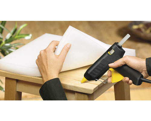 Pistolet à colle chaude collant de la mousse sur une chaise en bois