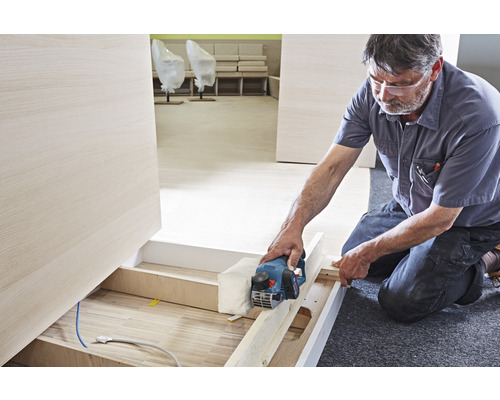 Artisan rabotant du bois avec un rabot électrique