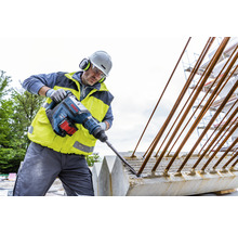 Ein Bauarbeiter arbeitet mit einem Bosch Bohrhammer an einem Betonfundament mit Bewehrungsstahl.