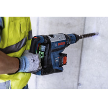 Ein Arbeiter bohrt mit einem Akku-Bohrhammer ein Loch in eine Betonwand. Bosch Logo.