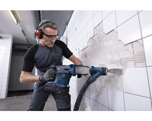 Mann mit Schutzbrille und Kopfhörern beim Entfernen von Fliesen mit einem Akku Bohrhammer von Bosch