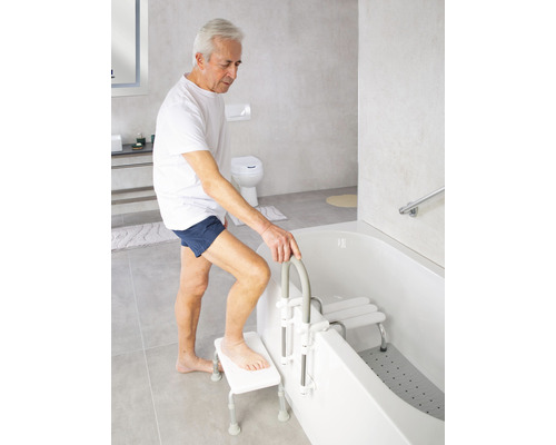 Mann benutzt Badewannenlifter und Badewannensitz in einem hellen Badezimmer.