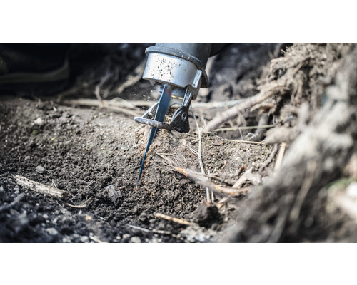 Eine Säbelsäge schneidet eine Wurzel im Erdreich.