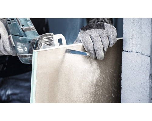 Eine Person schneidet eine Gipskartonplatte mit einer Säge.