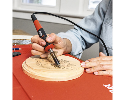 Personne utilisant un outil de pyrogravure sur une rondelle de bois