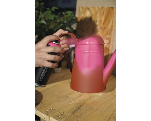 De la peinture en aérosol est appliquée sur un arrosoir