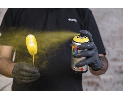 Une personne vaporise un objet avec un aérosol de peinture.