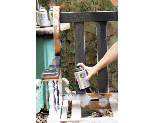 Une personne vaporise un banc en bois avec un aérosol de peinture