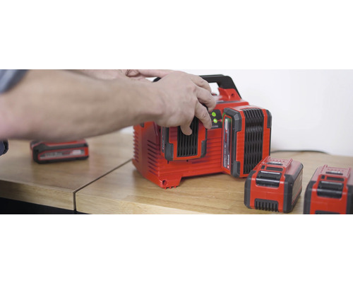 Chargeur de batterie avec plusieurs batteries sur une table en bois.