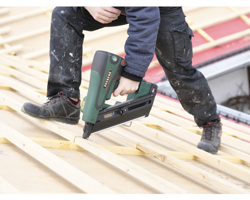 Eine Person verwendet einen Prebena Nagelapparat auf einer Holzkonstruktion.
