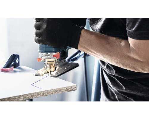 Eine Stichsäge schneidet eine Linie in ein Werkstück. Der Benutzer trägt Handschuhe.