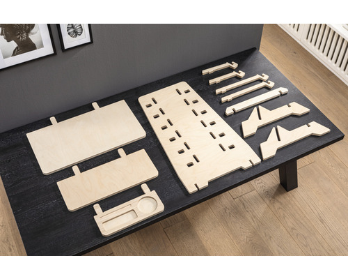 Einzelteile eines höhenverstellbaren Schreibtischaufsatzes aus Holz auf einem Tisch