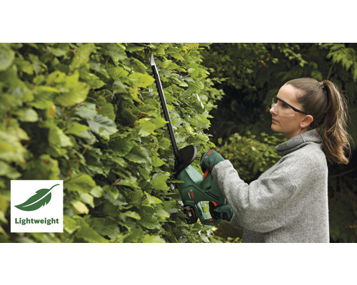 Frau schneidet Hecke mit einer Akku-Heckenschere