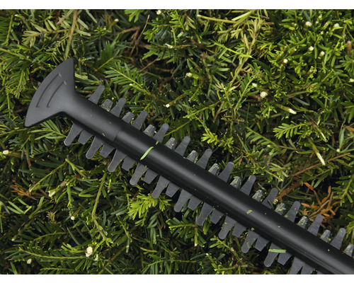 Detailaufnahme einer Heckenschere über grünen Blättern