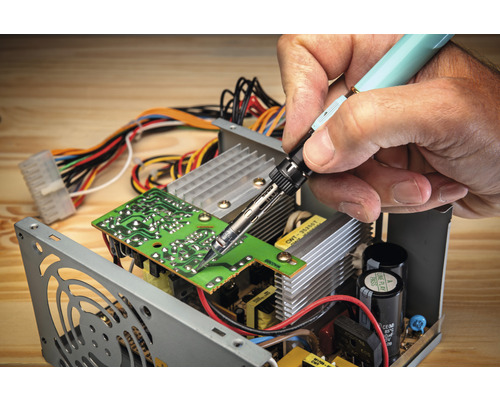 Lötgerät im Einsatz auf einer Platine innerhalb eines Computernetzteils.