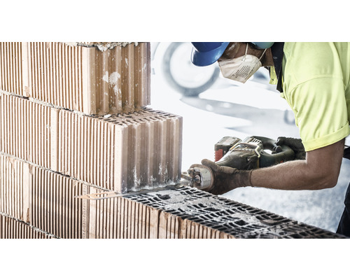 Ein Bauarbeiter sägt einen Ziegel mit einer Säge.