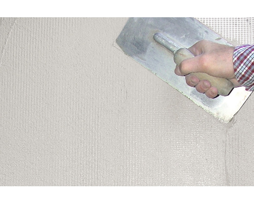 Eine Person glättet Putz mit einer Glättkelle auf einer Wand.