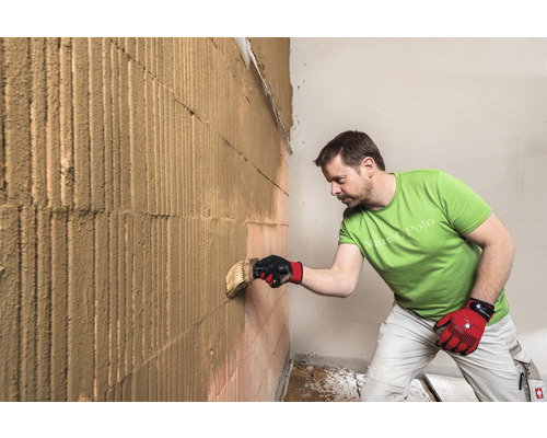 Mann trägt Putz auf eine Ziegelwand auf