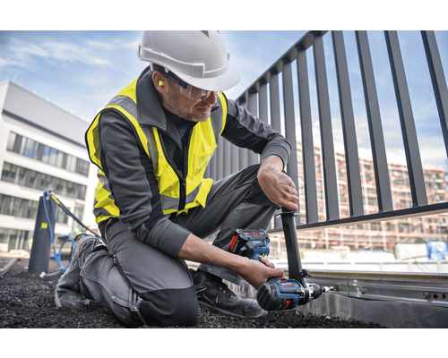 Un artisan fixe une balustrade avec une visseuse sans fil.