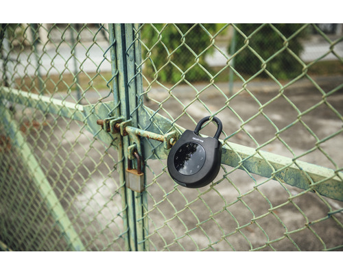 Un cadenas numérique à anse igloohome est accroché à un grillage.