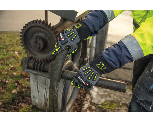 Gants de travail KinetiXx tenant une barre de métal devant une roue dentée
