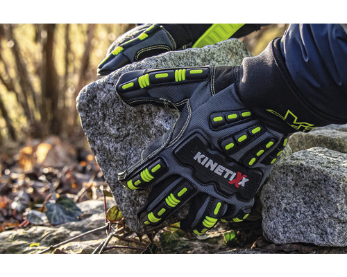 Une paire de gants de travail KinetiXx gris tient une pierre