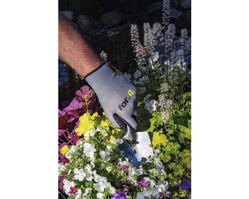 Personne portant des gants de jardin et une plantoir en train de planter des fleurs