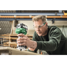 Mann verwendet Oberfräse an Holzbrett. Hikoki Logo.