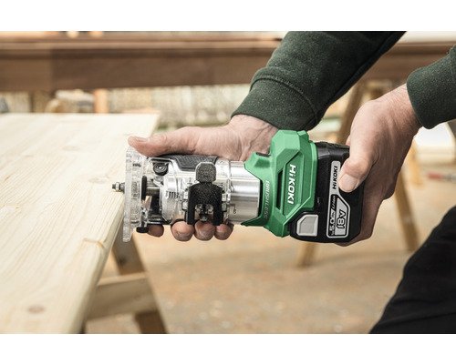 Person hält eine Akku Oberfräse beim Bearbeiten eines Holzbretts