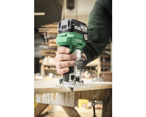 Eine Person benutzt eine Oberfräse von HiKOKI auf einem Holzbrett.